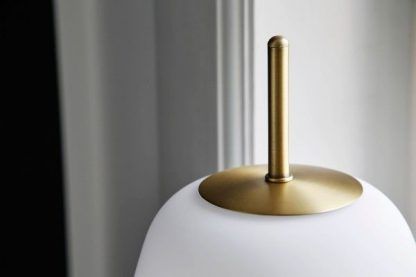 biała szklana lampa stołowa na złotej podstawie
