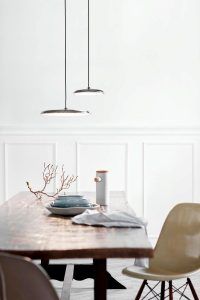 dwie srebrne lampy nad sosnowym stołem