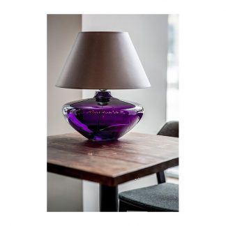 fioletowa owalna lampa stołowa na ciemnym stole
