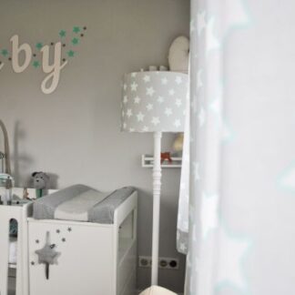Dziecięca lampa podłogowa Grey Stars z abażurem w biało-szary wzór gwiazdek, ustawiona w jasnym pokoju niemowlęcym obok przewijaka i białej komody, uzupełniająca wystrój z napisem "baby"na ścianie i pastelowymi dekoracjami.