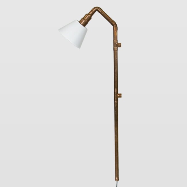 miedziane rurki i lampa na ścianę z białym kloszem