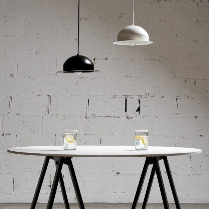 Okrągłe lampy wiszące nad stołem w tle betonowej ściany