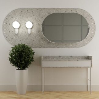 Kinkiet Kuul D,nowoczesny, biały z okrągłymi kloszami zamontowany na betonowej ramie lustra w przedpokoju. Minimalistyczna lampa ścienna o prostym, geometrycznym kształcie, idealnie komponująca się z terrazzo we wnętrzu z jasną konsolą i dekoracyjną rośliną.