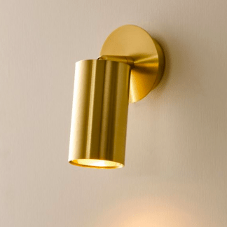 Złoty, elegancki kinkiet w kształcie tuby zamontowany na ścianie.