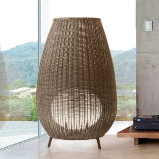 Duża lampa stojąca z plecionej syntetycznej wikliny w kształcie amfory na trójnożnej podstawie w nowoczesnym wnętrzu.