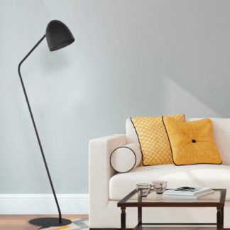 Czarna stojąca lampa Soho TK loft nad fotel i sofę z wygiętym ramieniem i stożkowym kloszem. Minimalistyczne oświetlenie podłogowe w stylu industrialnym przy białej kanapie z żółtymi poduszkami. Idealna lampa do czytania w salonie.