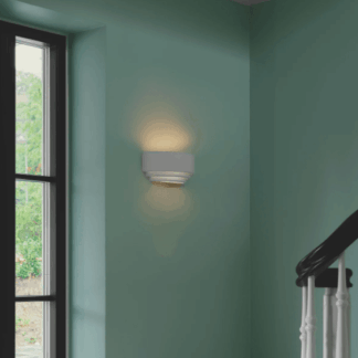 Gipsowy kinkiet Lancio Oblong Nordlux na miętowej ścianie przy schodach. Biała, minimalistyczna lampa ścienna z eleganckim, rozproszonym światłem tworzącym przytulną atmosferę. Nowoczesne oświetlenie dekoracyjne do wnętrz domowych.