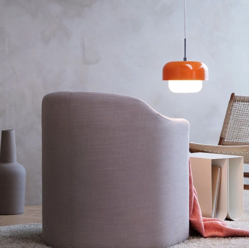 Nad stolikiem unosi się pomarańczowa lampa wisząca Haipot