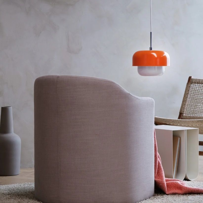 Nad stolikiem unosi się pomarańczowa lampa wisząca Haipot