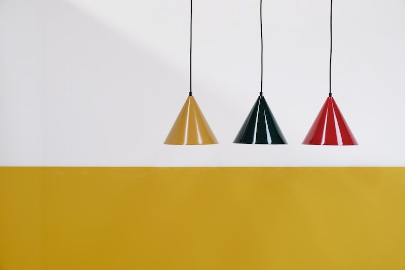 Żółta lampa wisząca w kształcie stożka nad stolikiem Ron od Dyberg Larsen