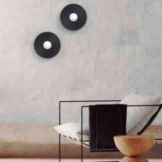 Kinkiety Randa czarne okrągłe 2 sztuki z białym szklanym kloszem opalowym LED, nowoczesne oświetlenie ścienne do salonu sypialni, lampy dekoracyjne minimalistyczne skandynawskie na szarą ścianę, plafony czarne matowe nad metalowym siedziskiem, aranżacja wnętrz industrialna loft.