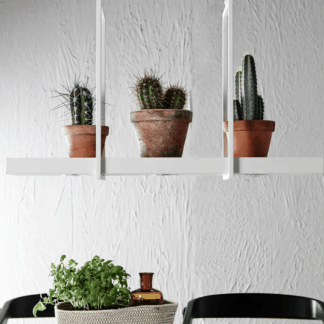 Biała, boho lampa wisząca Tray z funkcją półki, na której ustawione są trzy kaktusy w terakotowych doniczkach, zawieszona nad stołem z roślinami ziołowymi w koszyku i czarnymi krzesłami, na tle białej, teksturowanej ściany