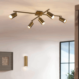 Nowoczesna złota lampa sufitowa Marley 5 typu spot z pięcioma regulowanymi reflektorami LED na krzyżujących się ramionach, wisząca w jasnym salonie obok pasującego złotego kinkietu, idealna do oświetlenia punktowego przestrzeni dziennej