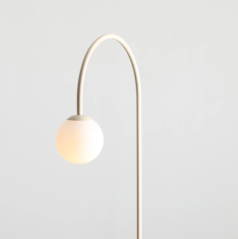Stylowa lampa podłogowa Una w kremowym kolorze z kulistym kloszem na wygiętym ramieniu