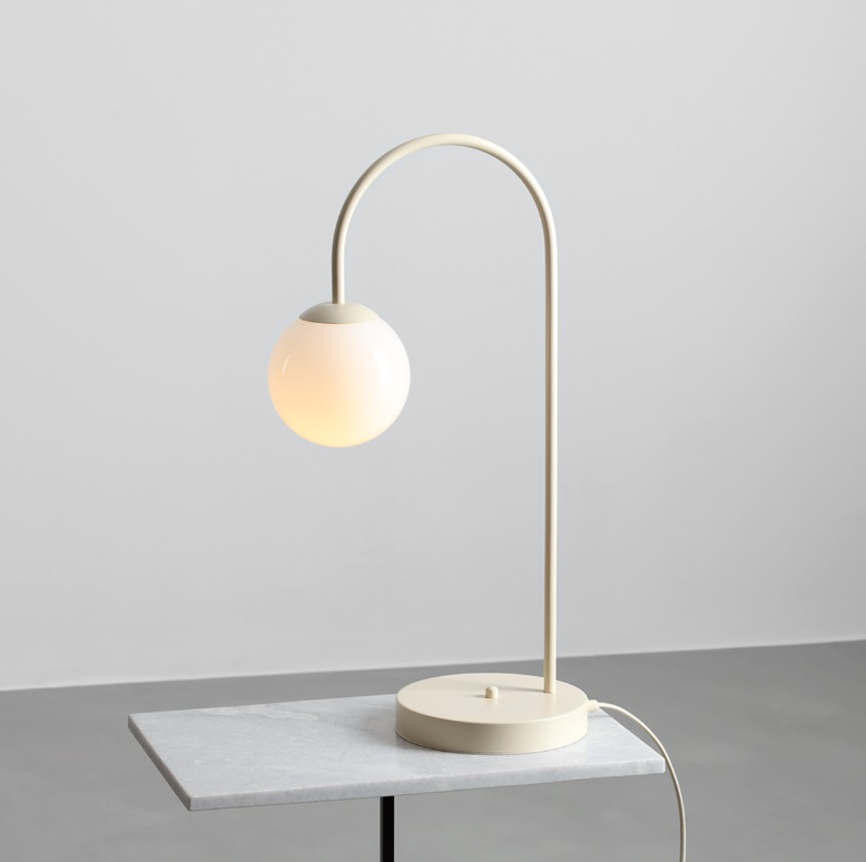 Stołowa lampa Una w kremowym kolorze – kulisty klosz na łukowatej podstawie